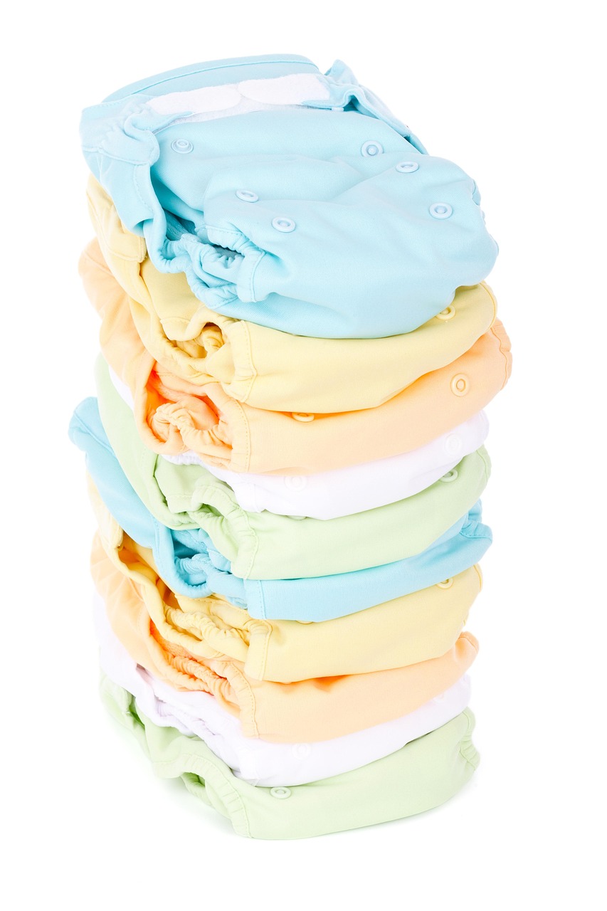 Stack of colorful cloth diapers in pastel shades neatly folded and arranged on a white background.