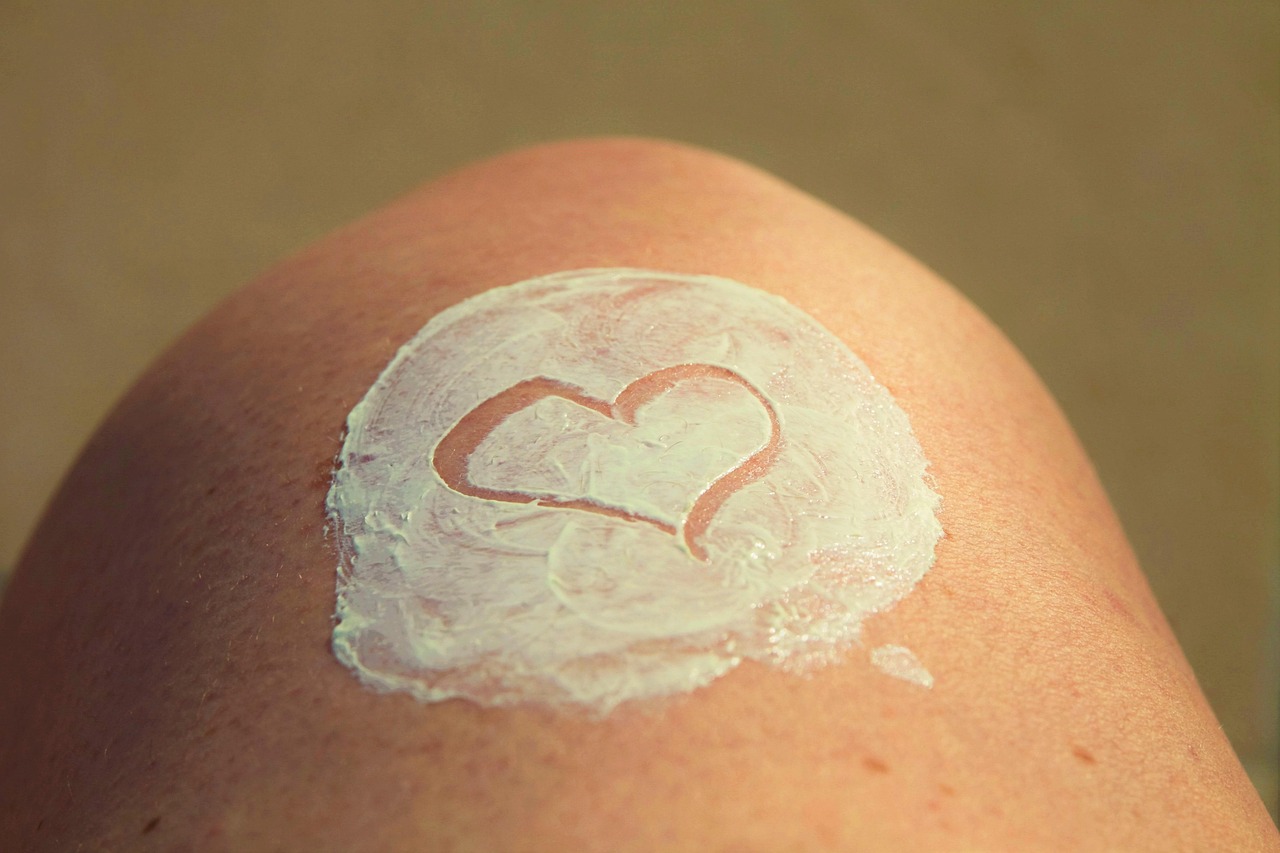 DIY natural sunscreen made with beef tallow, shown on skin with a heart shape drawn into the creamy mixture.